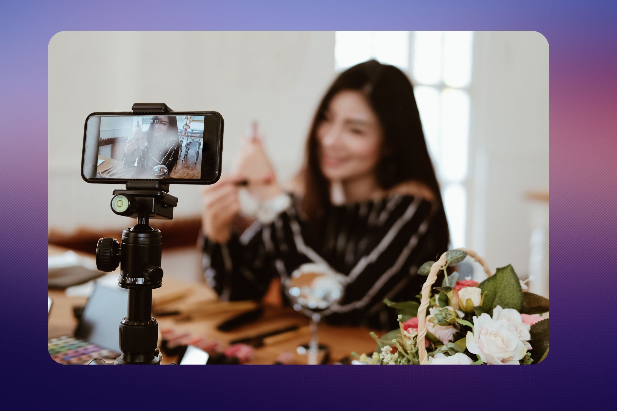 A woman filming herself on a phone on a tripod at a table of flowers